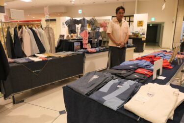 会場に並ぶ各縫製業者の商品=岡山県津山市で