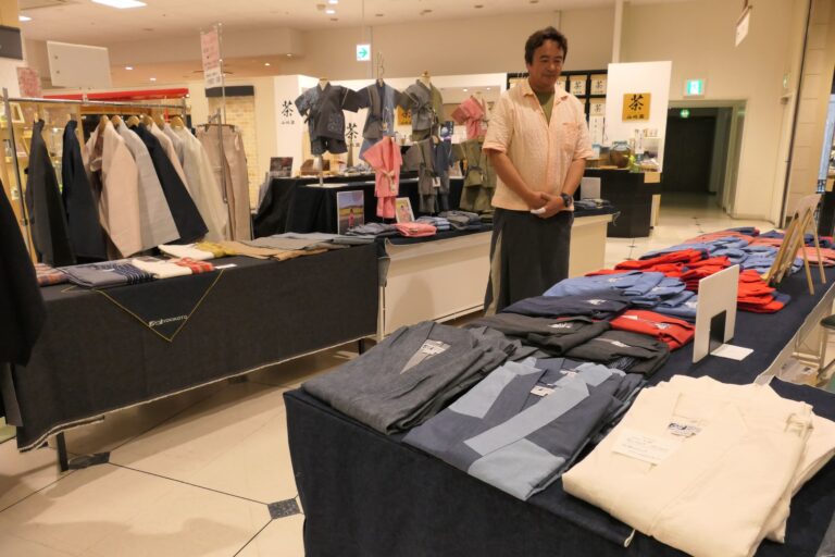 会場に並ぶ各縫製業者の商品=岡山県津山市で
