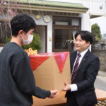 立正青葉学園の子どもたちへ靴を手渡す山田養蜂場の従業員有志＝岡山県津山市で