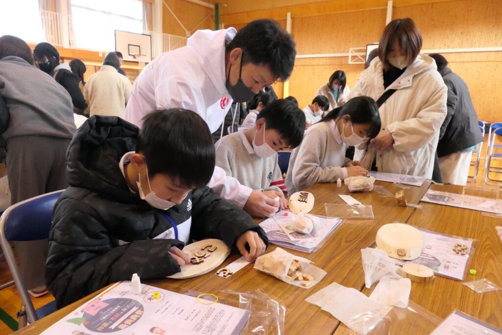 間伐材を使ったネームプレートを製作する親子