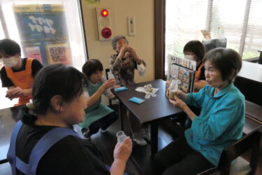 コーヒー牛乳を飲みながら会話を楽しむお年寄り=岡山県津山市で