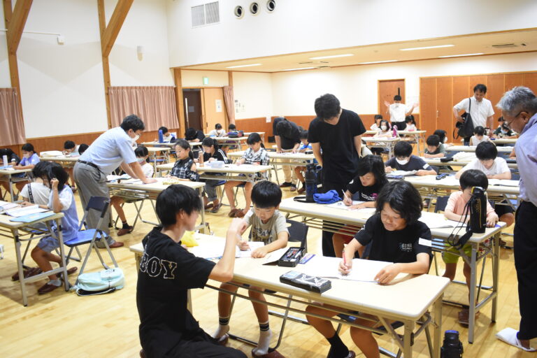 中高生や社会人に教えてもらいながら夏休みの宿題に取り組む子どもたち=岡山県津山市で