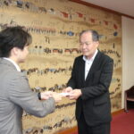 光井市長にクーポン券の目録を手渡す江見管理本部長（右）＝岡山県津山市で