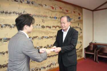 光井市長にクーポン券の目録を手渡す江見管理本部長（右）＝岡山県津山市で
