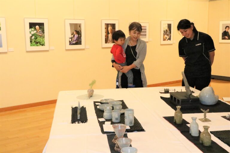 写真や陶芸などの作品に見入る来場者=岡山県勝央町で