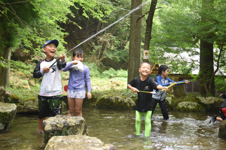 自作の水鉄砲で水遊びを楽しむ子どもたち=岡山県津山市で