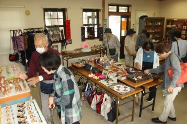 人形や布製品に見入る人々=岡山県真庭市、JR美作落合駅で