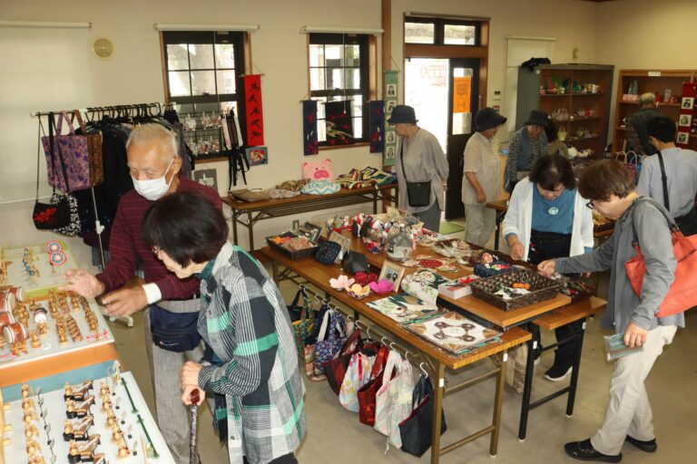 人形や布製品に見入る人々=岡山県真庭市、JR美作落合駅で