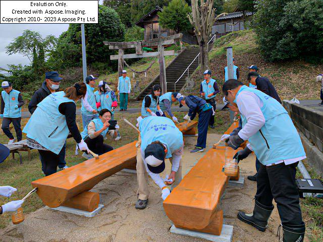 寄贈品の木製ベンチに保護剤を塗装する参加者=岡山県津山市で