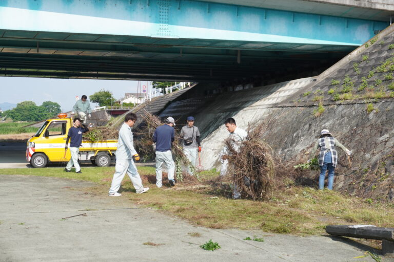 吉井川河川敷でのり面の雑草を刈り取る市民=岡山県津山市で