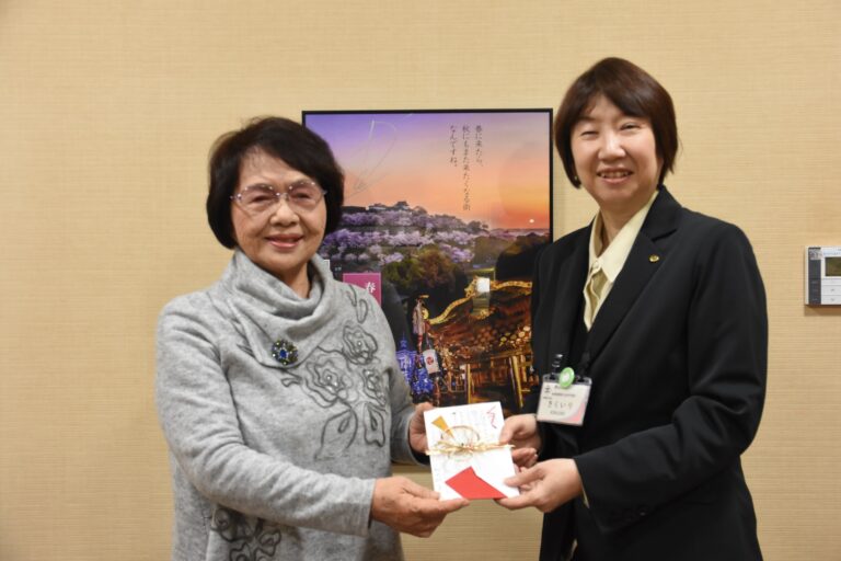 感謝の気持ちを込めて図書館に寄付をした小野田さん（左）=岡山県津山市で