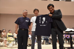 箕作Ｔシャツを笑顔で手にする藤岡さん=岡山県津山市で