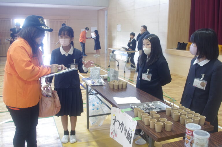 参加者に非常食について説明する児童たち=岡山県美咲町で