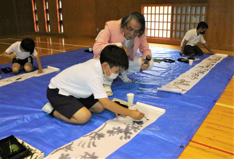 自由に墨絵を描く児童たちと武藤さん