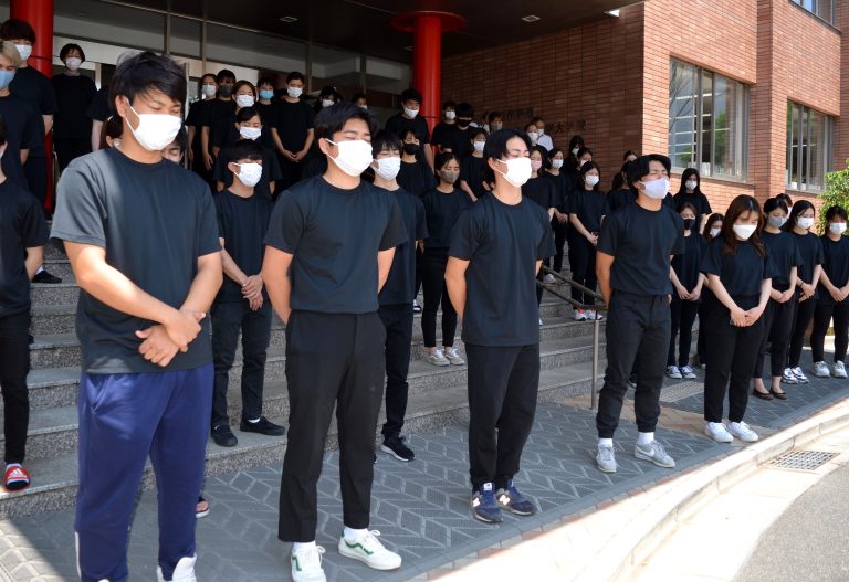 沖縄の方角を向いて黙とうをささげる学生たち