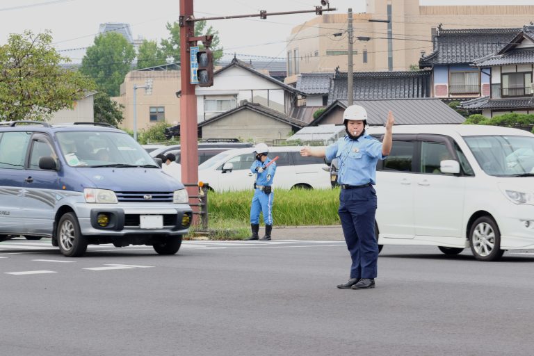 手信号で車を誘導する署員