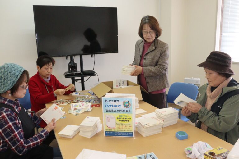 発送するはがきや切手を箱詰めする女性部員＝岡山県津山市で