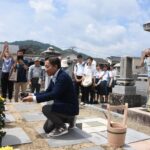 墓前にコーヒーを供え、手を合わせる参加者=岡山県津山市で