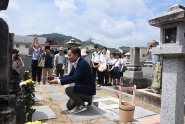墓前にコーヒーを供え、手を合わせる参加者=岡山県津山市で