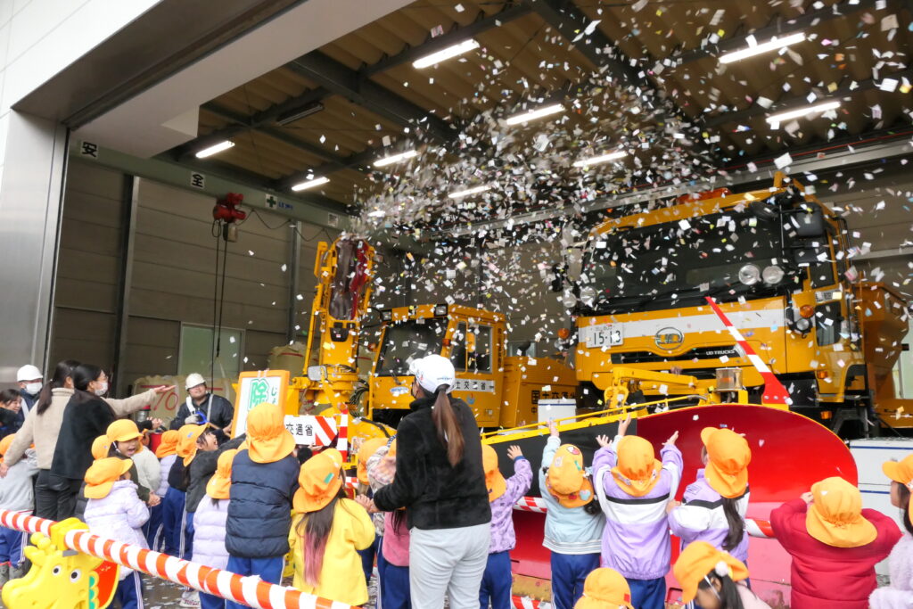 小型ロータリー除雪車から吹き出した紙吹雪に喜ぶ子どもたち