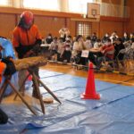 チェーンソーで丸太を切る実演を見る児童ら=岡山県津山市で