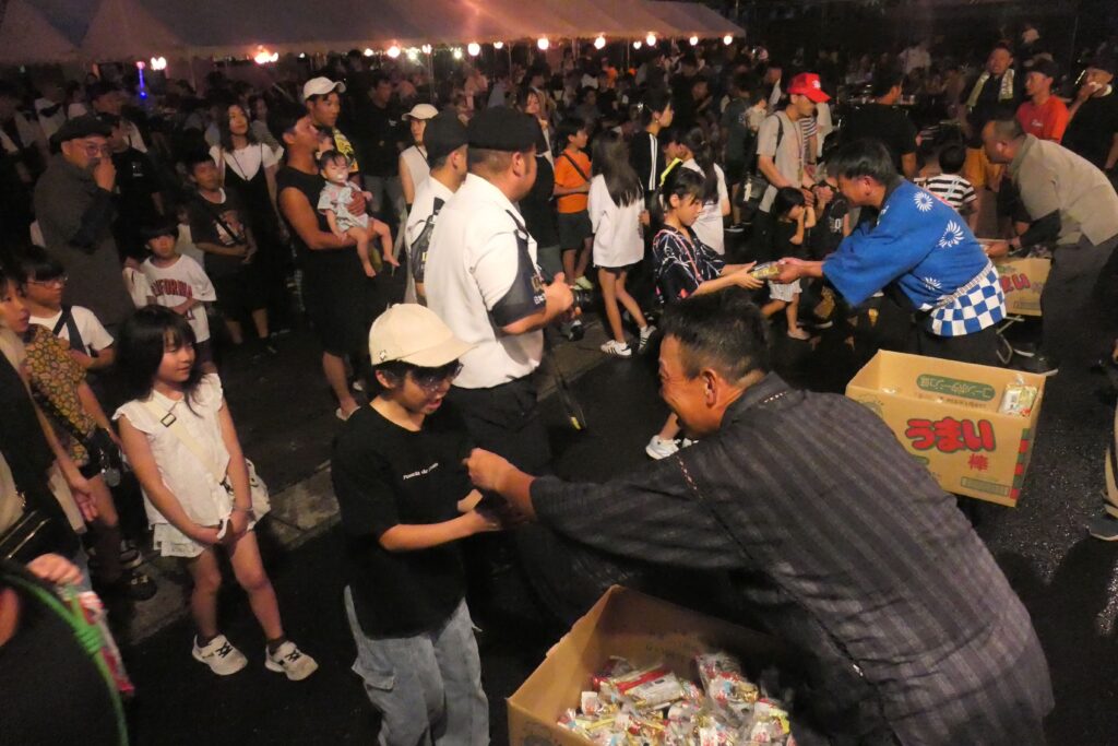 お菓子を配る倉本司令ら