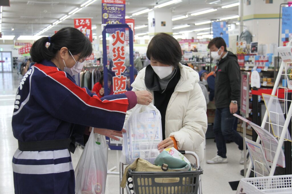 買い物客に啓発品を手渡す女性防火クラブ会員