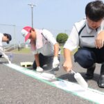駐車場の白線引きに汗を流す高校生＝岡山県津山市、勝北中学校で