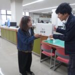 はがき回収箱の設置を依頼する無関副部長（左）=岡山県奈義町、奈義町役場で