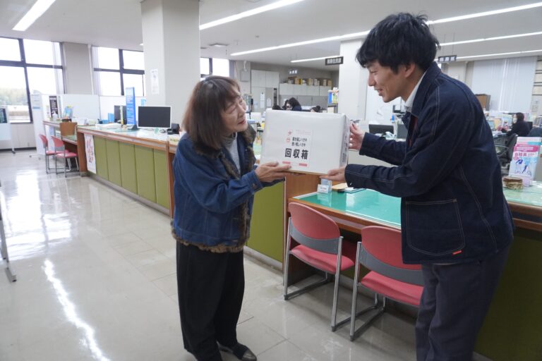 はがき回収箱の設置を依頼する無関副部長（左）=岡山県奈義町、奈義町役場で