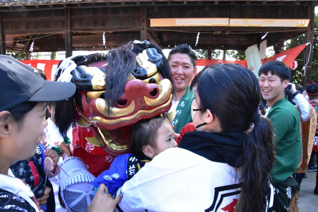 獅子に頭を噛んでもらう幼児