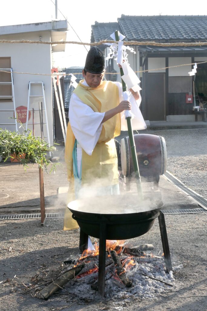 青竹の矛で湯をかき混ぜる吉田宮司