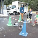 自転車型の人力発電機のペダルをこぐ子ども