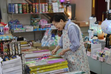 笑顔で花火を手に取る小坂ツヤ子さん