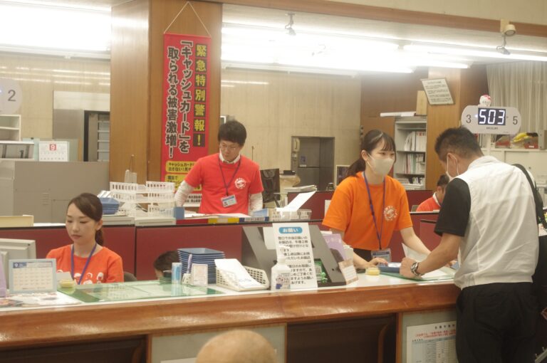 オレンジ色のTシャツ姿で窓口対応する信金職員=岡山県津山市で