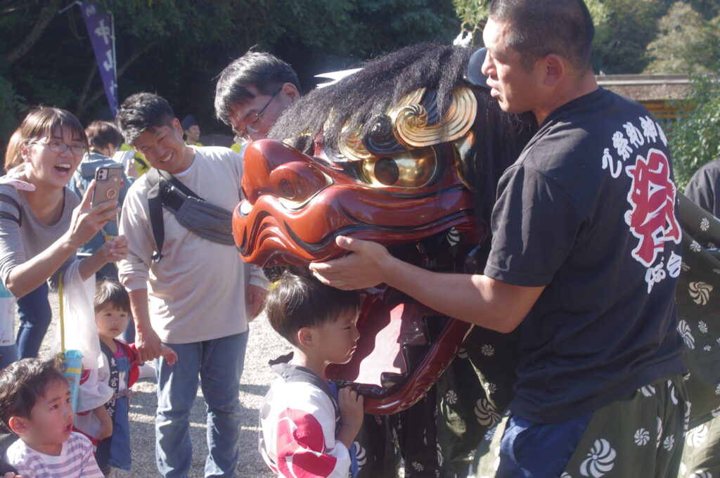 獅子舞に頭をかまれる子ども