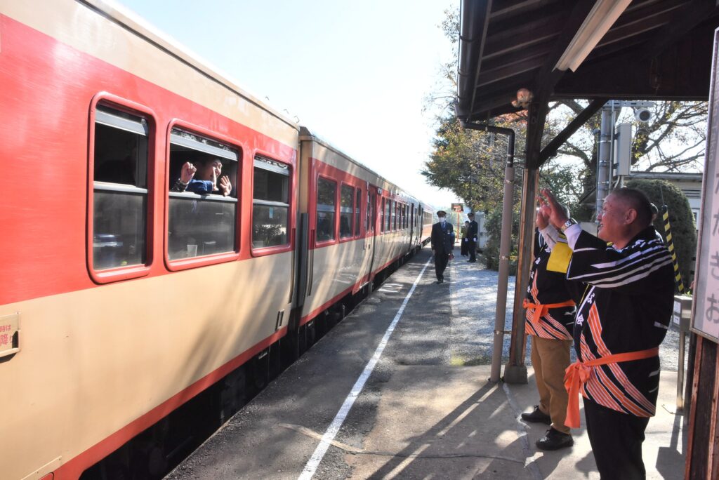 出発するノスタルジー車両を手を振りながら見送る人たち