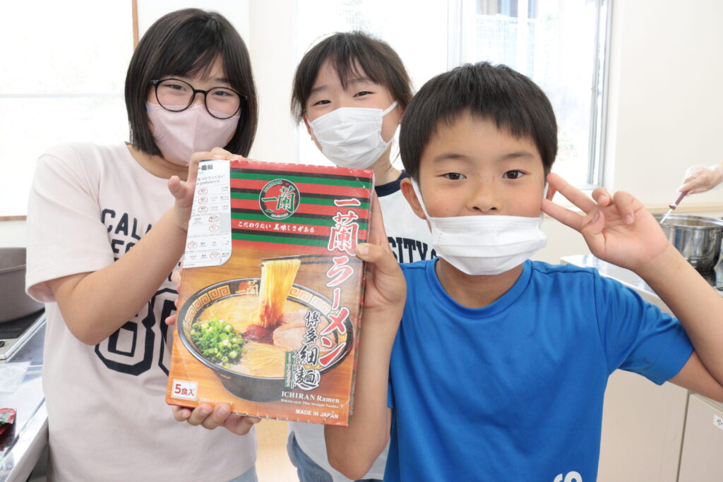 一蘭から寄贈されたラーメンを手にする子どもたち