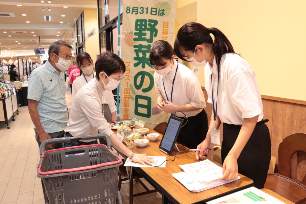 専用機器で野菜の摂取状況を測定する買い物客