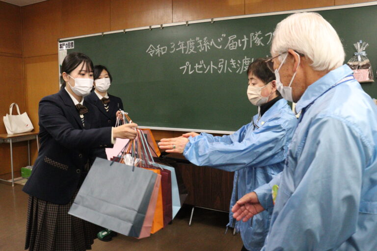 民生委員にプレゼンを預ける生徒たち