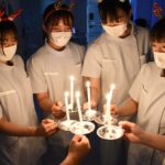 キャンドルの灯（ともしび）を分け合う学生たち=岡山県津山市川崎の津山中央看護専門学校で