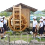 復活したせせらぎ水車を眺める成名小の6年生=岡山県津山市で