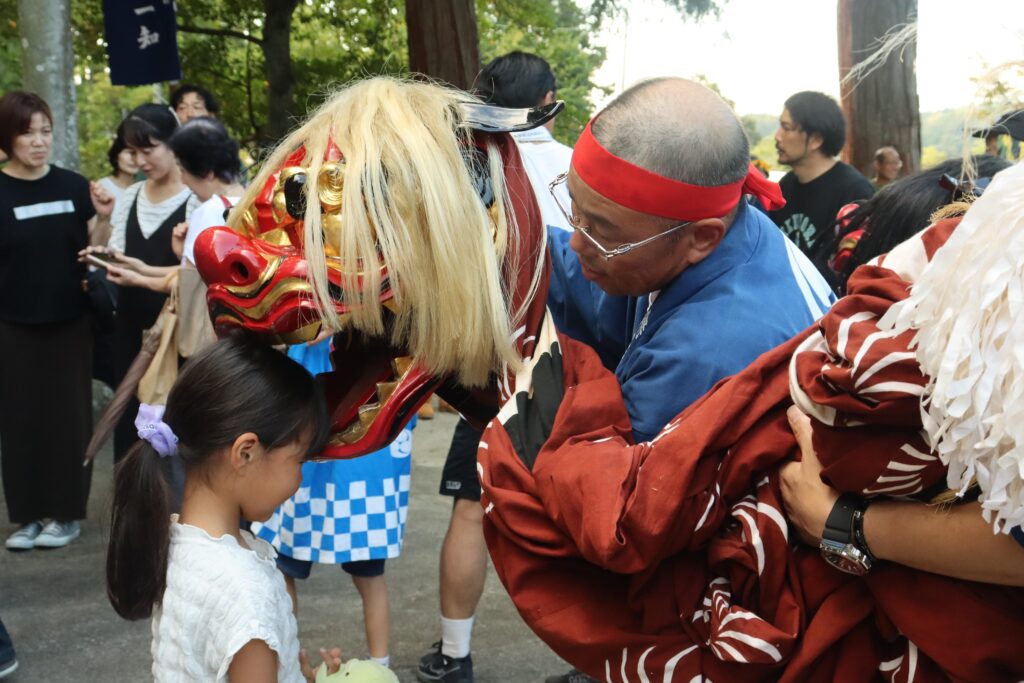 獅子舞にかまれる子ども