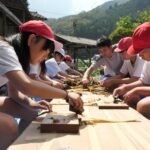 ミツマタの皮を丁寧に「へぐる」児童=岡山県津山市で