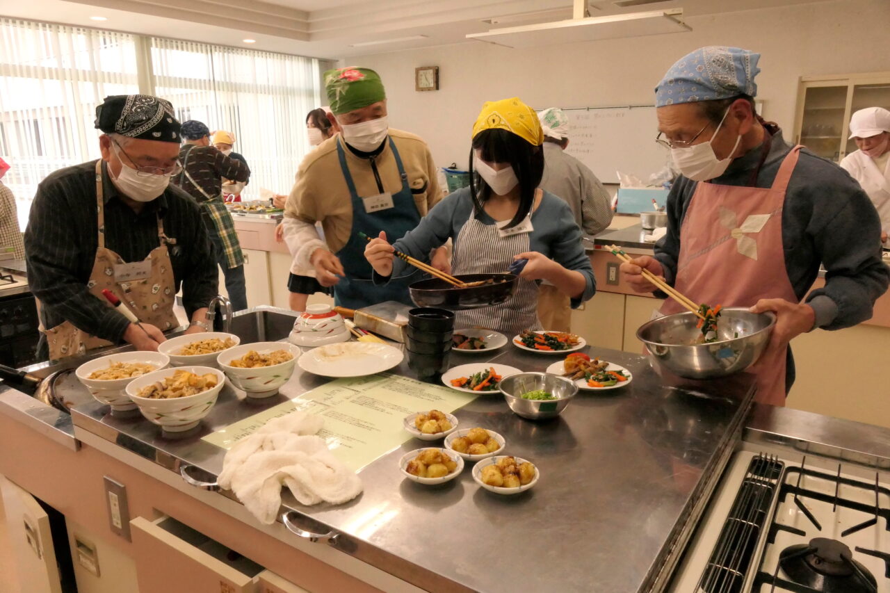 協力して調理する高校生と男性たち=岡山県津山市で