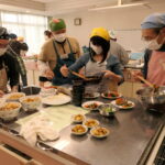 協力して調理する高校生と男性たち=岡山県津山市で