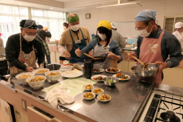 協力して調理する高校生と男性たち=岡山県津山市で