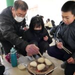 地域の人と一緒におにぎりを焼く児童=岡山県津山市で