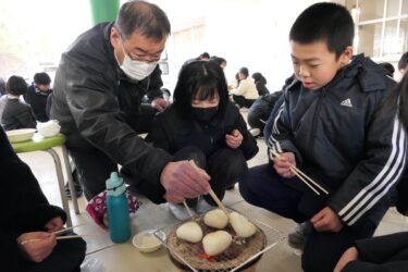 地域の人と一緒におにぎりを焼く児童=岡山県津山市で