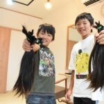 切った髪の束を手にする兄弟